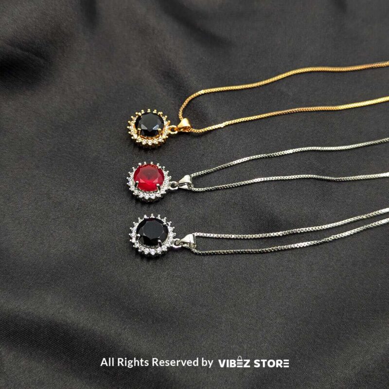 Round Gemstone Locket with Crystal Halo 1 Three round gemstone lockets with crystal halos, displayed on gold-tone and silver-tone chains against a black fabric background.