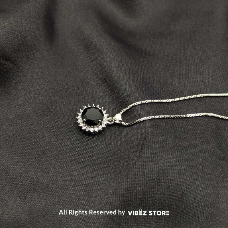 Round Gemstone Locket with Crystal Halo 4 Three round gemstone lockets with crystal halos, displayed on gold-tone and silver-tone chains against a black fabric background.