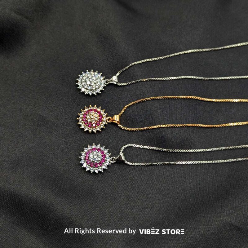 Multi-Color Gemstone Halo Lockets 1 A collection of three gemstone lockets in clear, gold-pink, and silver-pink tones, each surrounded by a dazzling crystal halo, displayed on a black fabric background.