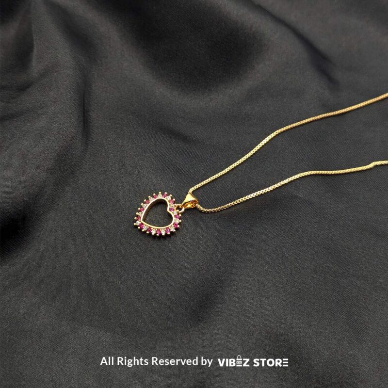 Gold Heart Frame Locket with Pink Gem Accents 2 Gold heart-shaped open-frame locket with pink gemstone accents displayed on a black fabric background.