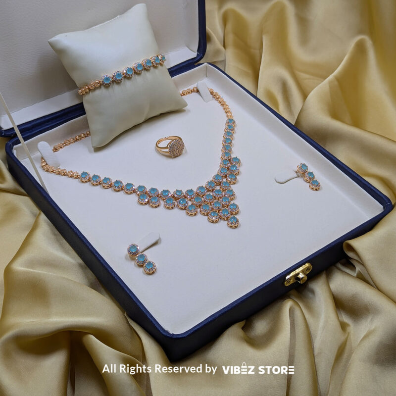 Elegant Aqua Blue Gemstone Jewelry Set 2 Gold-tone jewelry set with aqua blue gemstones, including a necklace, earrings, bracelet, and ring, elegantly displayed by Vibez Store.