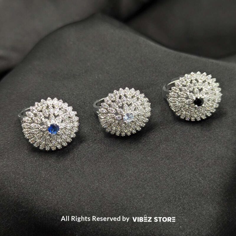 Dazzling Floral Crystal Rings 1 Silver-tone floral rings with crystal accents and central gemstones in sapphire blue, clear crystal, and jet black, beautifully displayed by Vibez Store.