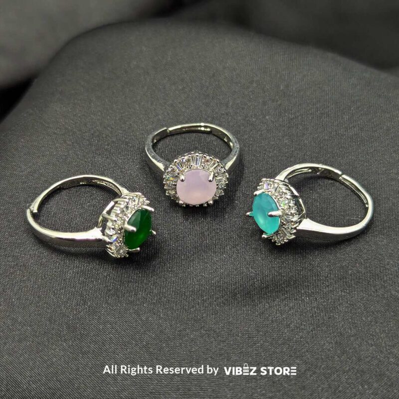 Elegant Halo Gemstone Adjustable Rings 1 Silver-tone halo rings with radiant gemstones in emerald green, rose pink, and aquamarine blue, encircled by sparkling crystals, showcased by Vibez Store.