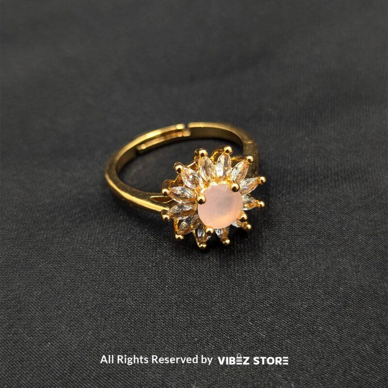 Golden Sunburst Ring with Pink Center Stone 1 Golden ring with a soft pink center stone and sunburst-style crystal accents, exuding elegance and charm from Vibez Store.