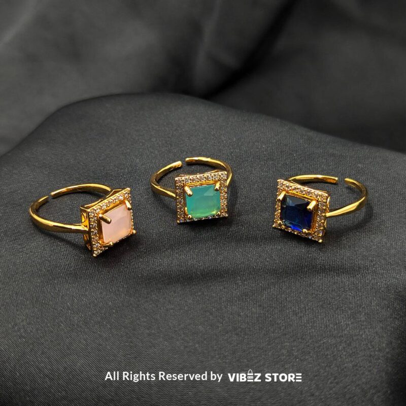 Elegant Square Gemstone Rings (Adjustable, Color Variations Available) 1 Gold-tone adjustable rings with square gemstones in rose pink, aqua blue, and sapphire variations, elegantly displayed by Vibez Store.