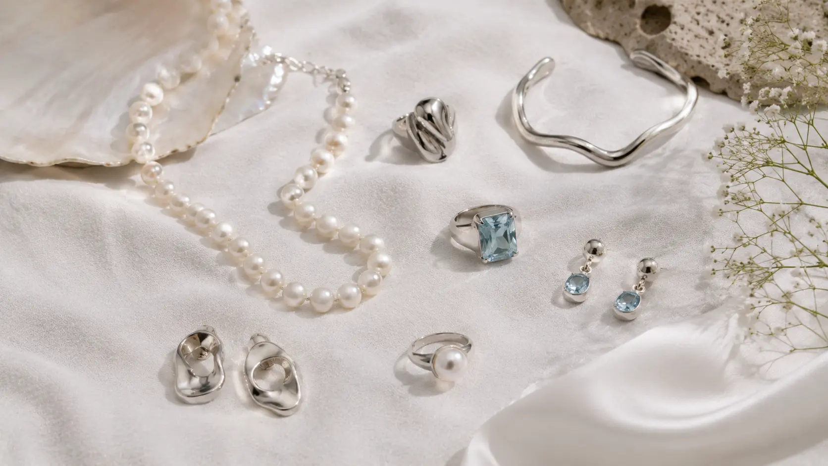 What Jewellery to Wear with Black, White and Pastel Outfits? 4 Pearl jewellery aquamarine stones and silver accessories arranged on white textured fabric