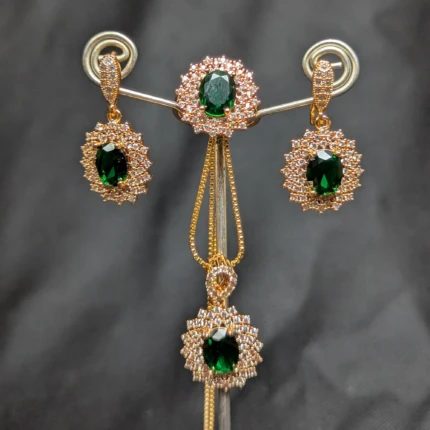 Emerald green zircon style jewellery set with gold tone earrings pendant and ring close up