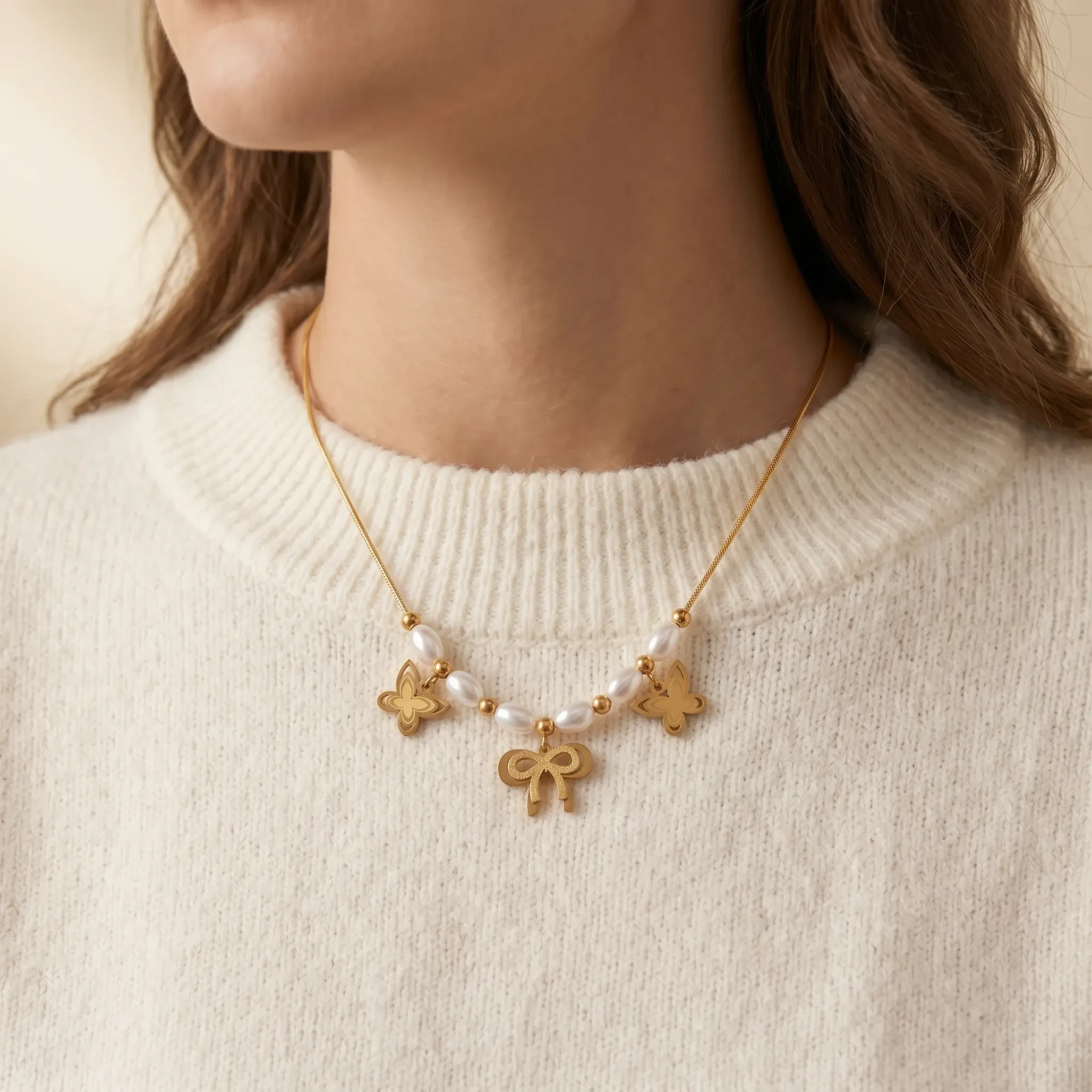 Model Wearing Gold Pearl Butterfly Charm Necklace Model wearing gold pearl butterfly charm necklace with cream sweater