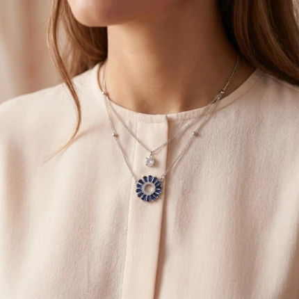 Model wearing silver blue layered circle pendant necklace with light outfit