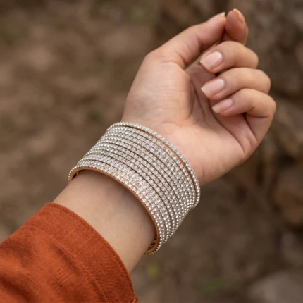 Model wearing silver crystal bangles set on wrist with formal outfit