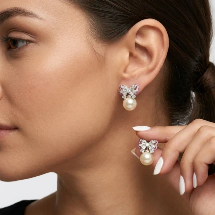 Model wearing silver pearl bow earrings with pink accents and pearl drop