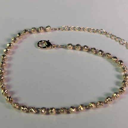 Close-up of gold-tone beaded anklet with lobster clasp and extension chain