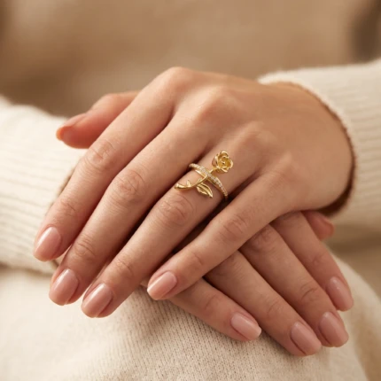 Woman wearing a gold-tone rose flower ring with crystal wrap band