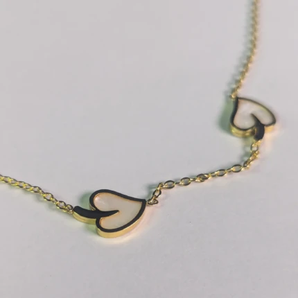 Close-up of gold-tone necklace with white heart-shaped charms