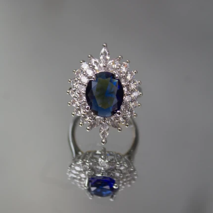 Front view of silver-tone ring with royal blue oval centre stone and clear crystal halo