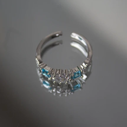 Angled view of silver-tone adjustable ring with blue and clear crystals