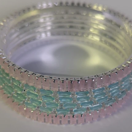 Angled view of silver-tone bangles with pink and aqua rectangular stones