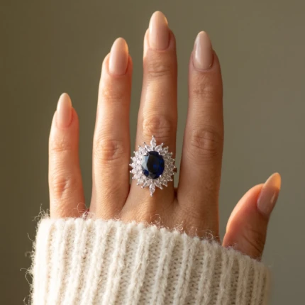 Woman wearing a silver-tone statement ring with royal blue oval stone and clear crystal halo